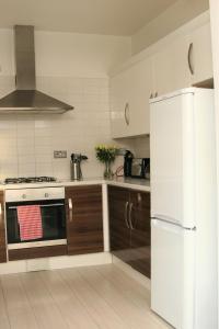 cocina con nevera blanca y armarios de madera en Twizell Lane, en Beamish