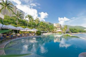 a swimming pool with chairs and umbrellas in a resort at Suites at Garza Blanca Preserve Resort & Spa in Puerto Vallarta