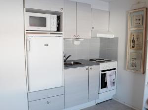 a kitchen with a white refrigerator and a microwave at TaloYlläs, Huonemajoitus in Äkäslompolo