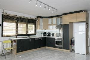 a kitchen with black cabinets and a white refrigerator at Villa NK in Paleo Tsifliki