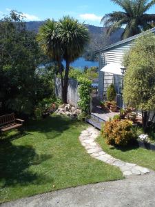 a garden with a bench and a tree and a house at The Tuai Suite Waikaremoana in Tuai