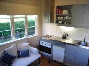 a kitchen with a couch and a sink and two windows at The Tuai Suite Waikaremoana in Tuai