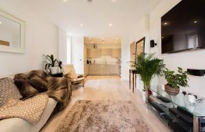 a living room with a large couch and a kitchen at Lovely 2 bed apartment 15mins from Bond St in London