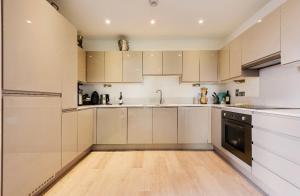a kitchen with white cabinets and a wooden floor at Lovely 2 bed apartment 15mins from Bond St in London