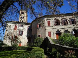 ein altes Steingebäude mit roten Fenstern und einem Turm in der Unterkunft Belvilla by OYO Castello di Robella in Robella