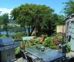 a woman standing in a garden with a table and a grill at The Tuai Suite Waikaremoana in Tuai