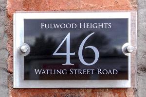 una señal en el costado de una pared de ladrillo con el número de personas y luces esperando en Fulwood Heights Apartments en Preston