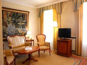 a living room with a tv and chairs and a table at Rezydencja Willa Park & Restauracja in Legnica