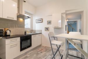 uma cozinha com armários brancos e uma mesa e cadeiras em Le Charme du médiéval dans un appartement cosy em Hyères