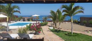 un complejo con piscina, palmeras y océano en Guille Bungalows, en Canoas de Punta Sal