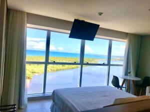 a bedroom with a large window with a view of the ocean at Paiva Flat Home Stay - Barra de Jangada in Recife