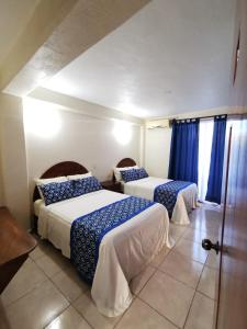 a hotel room with two beds and a window at Habitaciones del Pacifico in Zihuatanejo