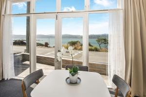 een eetkamer met een tafel en een groot raam bij Waterfront 2-bed cottage, Karaka Bays in Wellington