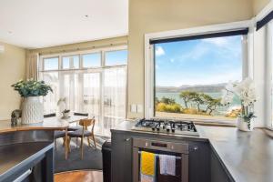 een keuken met een wastafel en een groot raam bij Waterfront 2-bed cottage, Karaka Bays in Wellington