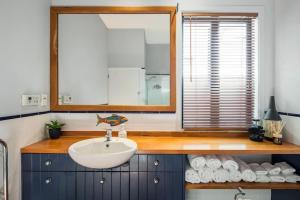 a bathroom with a sink and a mirror and towels at Waterfront 2-bed cottage, Karaka Bays in Wellington
