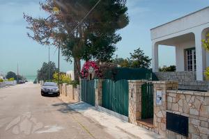 マリーナ・ディ・マンカヴェルサにあるVilletta Lungomare Gallipoli - Family Houseの柵の横の路上駐車