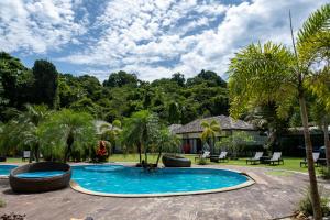 a swimming pool with palm trees and a house at The Reef Resort in Koh Kradan