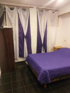 Schlafzimmer mit einem lila Bett und weißen Vorhängen in der Unterkunft CHE LOLITA HOUSE in Buenos Aires