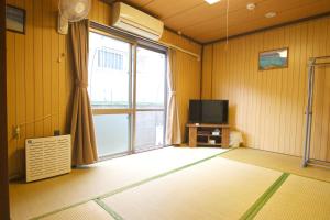 a room with a large window and a television at Okinawa Naha JinJin -沖縄伝統体験型宿じんじん- in Naha