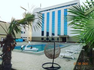 a large building with a swimming pool and palm trees at OydinPlaza Hotel in Namangan