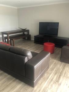 a living room with a black leather couch and a flat screen tv at Brand new 4br get away 5min to albury city in Lavington