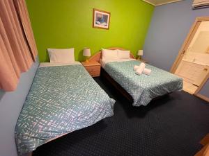 two beds in a room with green walls at City East Motel in Melbourne