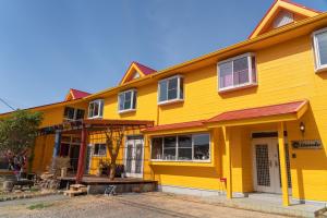 une maison jaune avec un toit rouge dans l'établissement Lodge Mondo, à Nishina