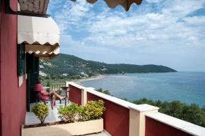 Un uomo seduto su un balcone che guarda l'oceano di Room in BB - Apraos Bay Hotel In Kalamaki Beach ad Apraos