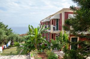 a red building with the ocean in the background at Room in BB - Apraos Bay Hotel In Kalamaki Beach in Apraos