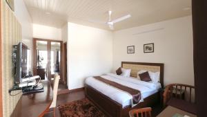 sypialnia z łóżkiem, biurkiem i telewizorem w obiekcie Hotel Sunny Cot Mussoorie Mallroad w mieście Mussoorie