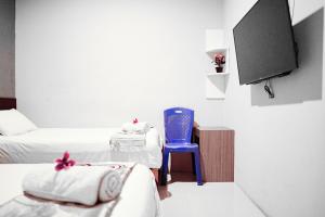 a room with two beds and a blue chair and a tv at Audah Syariah Residence Mitra RedDoorz in Surabaya