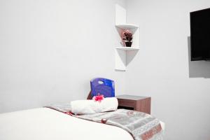 Habitación blanca con cama, silla y TV. en Audah Syariah Residence Mitra RedDoorz, en Surabaya