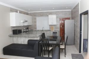 Royal Luxury Hotels and Apartments في Kitwe: مطبخ وغرفة طعام مع طاولة وثلاجة