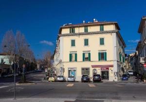 un grande edificio bianco su una strada cittadina con auto parcheggiate di Hotel San Marco a Prato