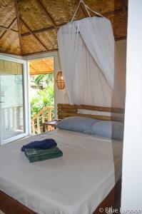 a bedroom with a bed with a white sheet and a window at Blue Lagoon Dive Resort in Sabang