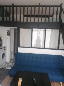 a blue couch in a living room with a loft at Le charme du bois in Écharcon