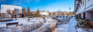 una calle cubierta de nieve con bancos y edificios en Dozamel, en Kołobrzeg