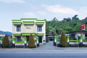 un bâtiment jaune et vert avec des arbres devant lui dans l'établissement OYO 1005 Hotel Kumala, à Samarinda