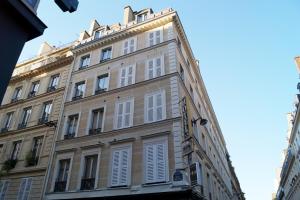a tall building with white shutters on it at Hotel Havane Opera in Paris