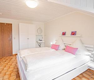 1 dormitorio con 1 cama blanca grande con almohadas rosas en Johannishof Wein-Café & Gästehaus, en Mesenich