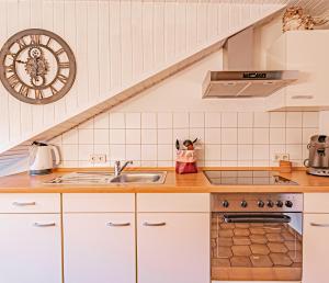 uma cozinha com um lavatório e um relógio na parede em Johannishof Wein-Café & Gästehaus em Mesenich