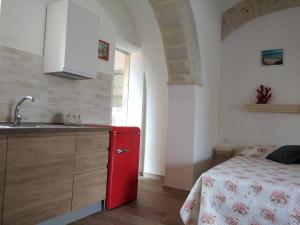 a kitchen with a red refrigerator next to a bed at Case Vacanze Mio Sogno in Favignana