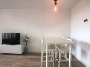 un tavolo bianco con sedie in una camera con TV di Residence Deurloo 53-08 a Cadzand Altre 9 foto