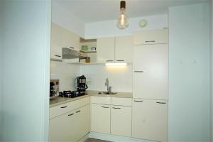 una cucina bianca con mobili bianchi e un lavello di Residence Deurloo 53-08 a Cadzand