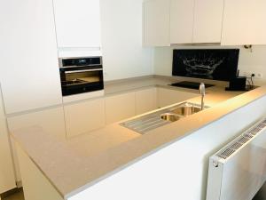a white kitchen with a sink and a stove at Even Aan Zee - Dukdalf in Nieuwpoort