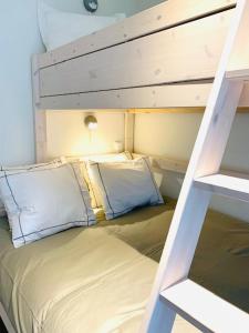 a bunk bed with two pillows and a ladder at Even Aan Zee - Dukdalf in Nieuwpoort