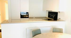 a kitchen with white cabinets and a table and chairs at Even Aan Zee - Dukdalf in Nieuwpoort