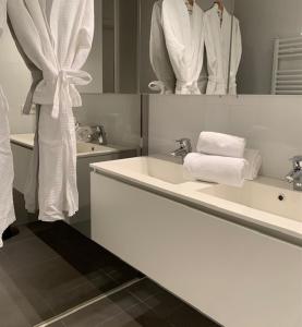 a bathroom with a sink and a mirror with towels at Even Aan Zee - Dukdalf in Nieuwpoort