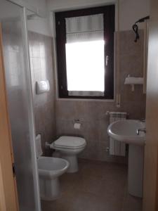 a bathroom with a toilet and a sink and a window at Porta Del Sole in Manfredonia