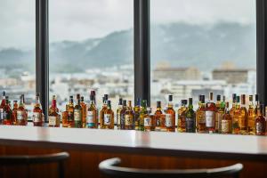 a row of bottles of alcohol sitting on a bar at The Gate Hotel Kyoto Takasegawa by Hulic in Kyoto